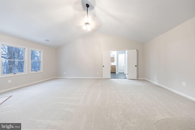 spare room featuring lofted ceiling and light colored carpet