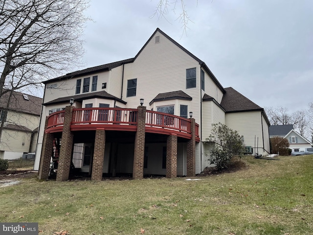 rear view of property with a wooden deck and a lawn