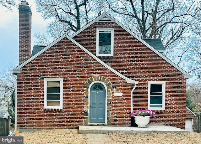 view of front of house featuring brick siding and a chimney