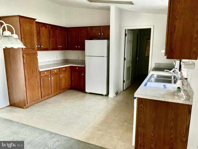 kitchen featuring sink, vaulted ceiling, and white fridge