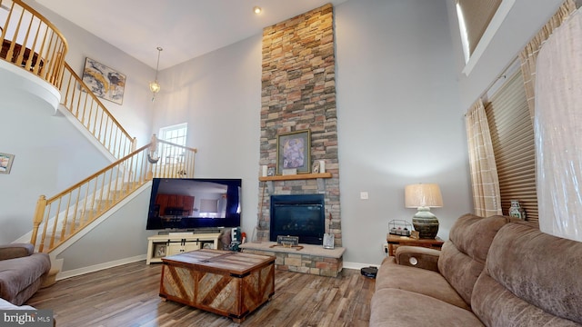 living room with a towering ceiling, wood-type flooring, and a fireplace