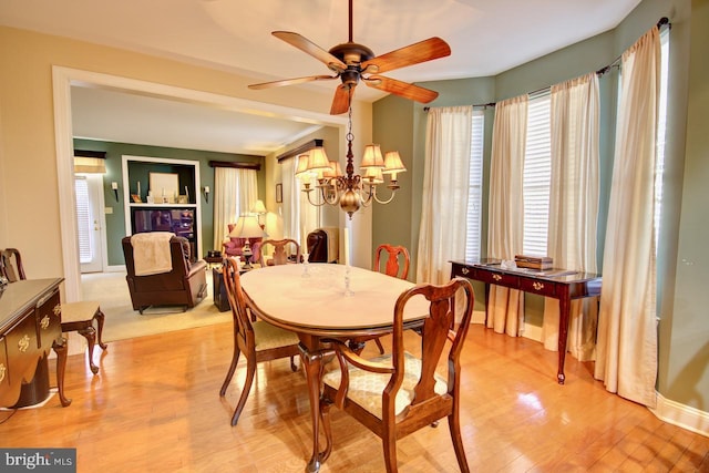 dining space featuring ceiling fan with notable chandelier and light hardwood / wood-style flooring