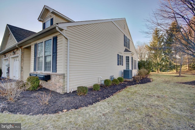 view of side of home featuring cooling unit, a garage, and a lawn