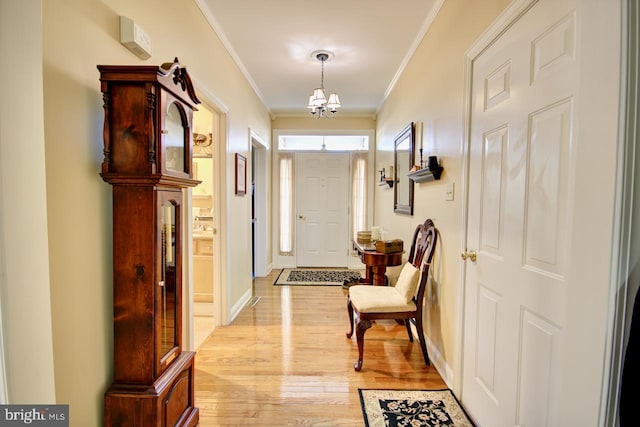 entryway with crown molding, an inviting chandelier, and light hardwood / wood-style floors