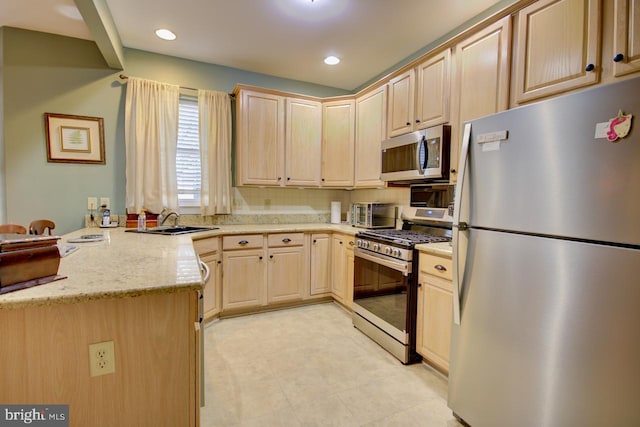 kitchen featuring light brown cabinetry, sink, light stone counters, appliances with stainless steel finishes, and kitchen peninsula