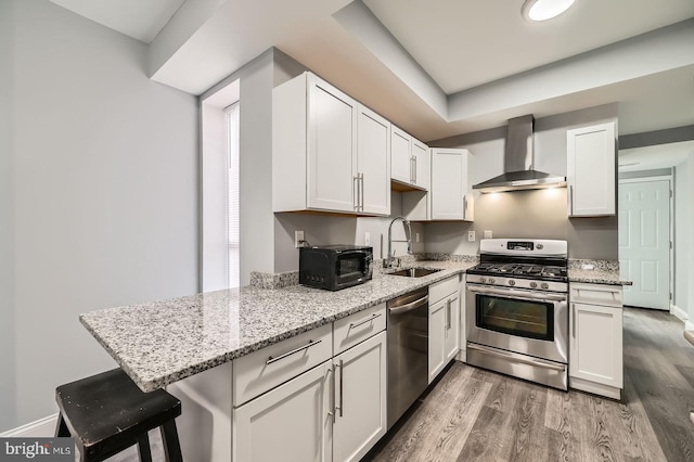 1631 N Montford Ave, Baltimore, MD 21213 - kitchen with wall chimney exhaust hood, a sink, light wood finished floors, light stone countertops, and stainless steel appliances