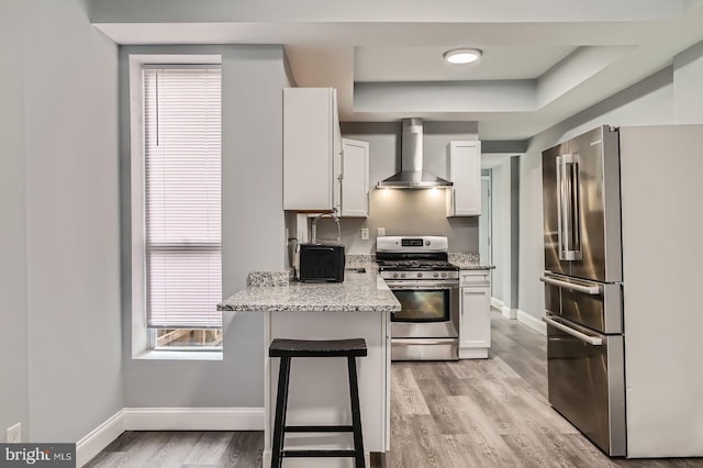 1631 N Montford Ave, Baltimore, MD 21213 - kitchen featuring light wood-style floors, wall chimney range hood, white cabinets, appliances with stainless steel finishes, and baseboards