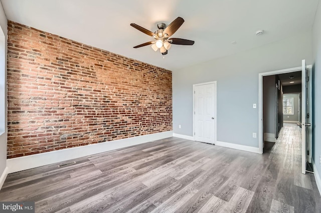 1631 N Montford Ave, Baltimore, MD 21213 - empty room featuring baseboards, brick wall, visible vents, ceiling fan, and wood finished floors