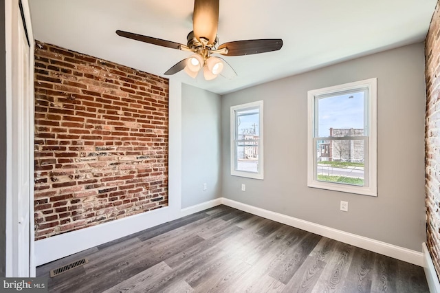 1631 N Montford Ave, Baltimore, MD 21213 - unfurnished room with visible vents, baseboards, brick wall, ceiling fan, and dark wood-type flooring