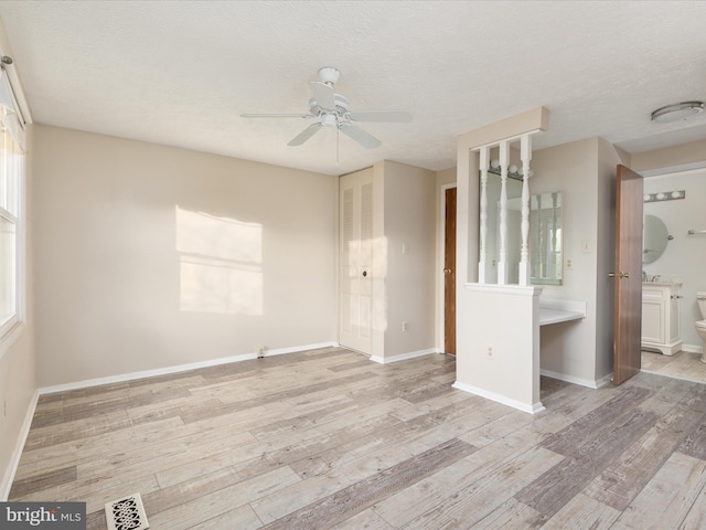 spare room with ceiling fan, light hardwood / wood-style floors, and a textured ceiling