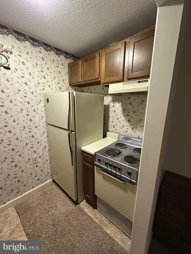 kitchen featuring white fridge, electric range, and a textured ceiling