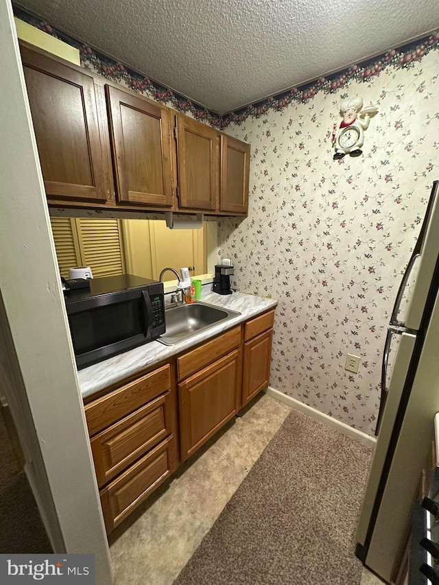 interior space featuring sink, stainless steel fridge, and a textured ceiling