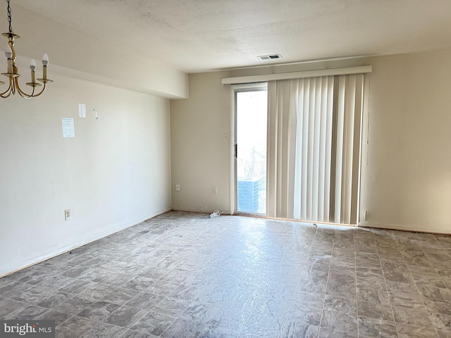 spare room with a notable chandelier and a textured ceiling