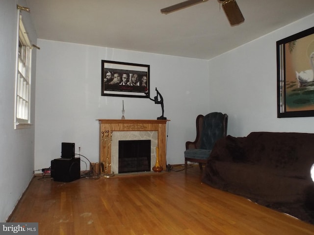 living room with hardwood / wood-style flooring, ceiling fan, and a premium fireplace