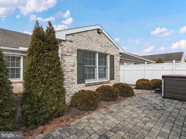 view of property exterior with a hot tub and a patio