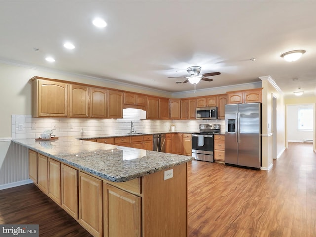 kitchen with stainless steel appliances, kitchen peninsula, sink, and stone counters