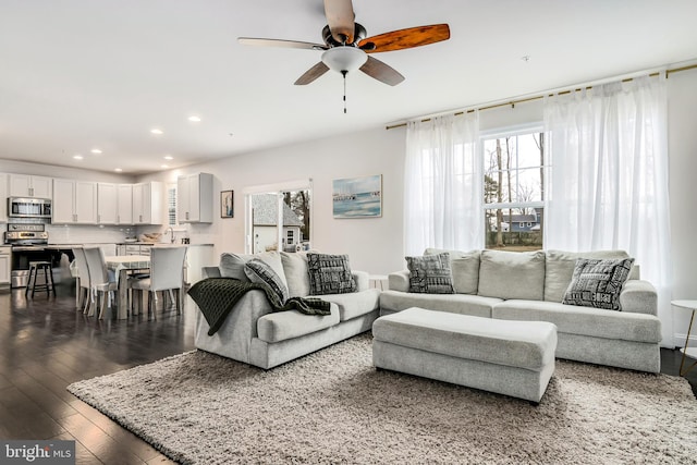 living room featuring dark wood-type flooring and ceiling fan