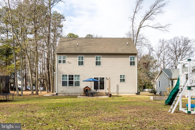 rear view of house with a yard, a playground, a patio area, and a trampoline