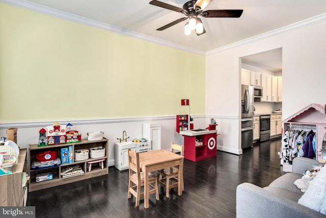 recreation room featuring ceiling fan, ornamental molding, and dark hardwood / wood-style floors