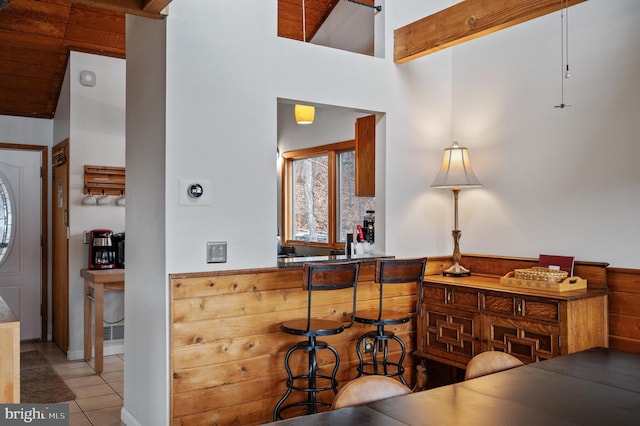 kitchen featuring a towering ceiling, kitchen peninsula, and light tile patterned floors