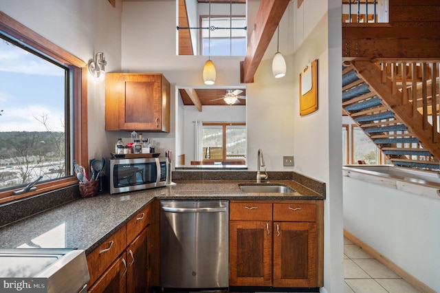 kitchen featuring sink, hanging light fixtures, light tile patterned floors, beamed ceiling, and stainless steel appliances