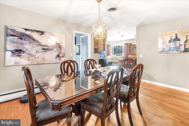 dining space featuring a baseboard heating unit, a chandelier, and light hardwood / wood-style flooring