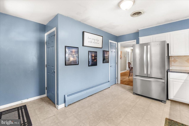 kitchen featuring stainless steel refrigerator, baseboard heating, decorative backsplash, and white cabinets