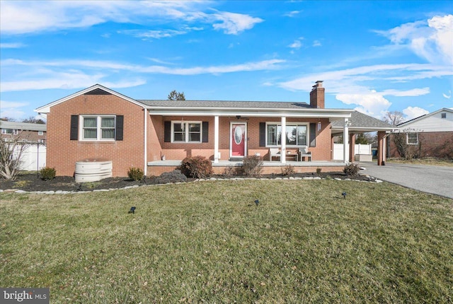 view of front of house featuring a carport, covered porch, and a front yard