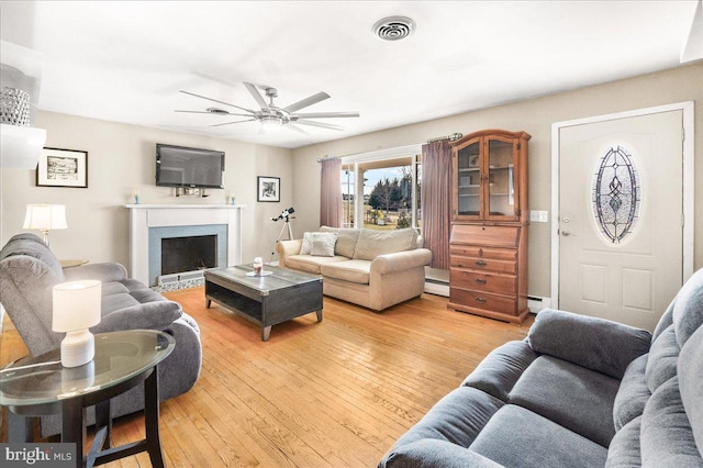 living room with a baseboard radiator, ceiling fan, and light wood-type flooring