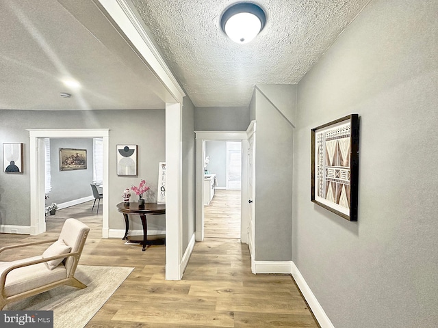 corridor featuring light hardwood / wood-style floors and a textured ceiling