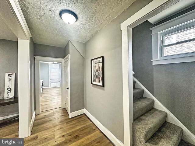 corridor with wood-type flooring and a textured ceiling