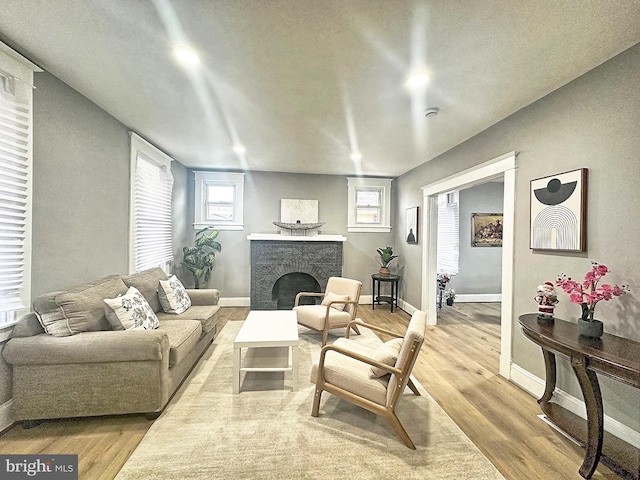 living room with a wealth of natural light, a fireplace, and light hardwood / wood-style floors