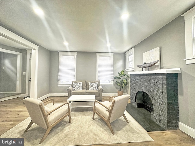 living area featuring a brick fireplace and light wood-type flooring