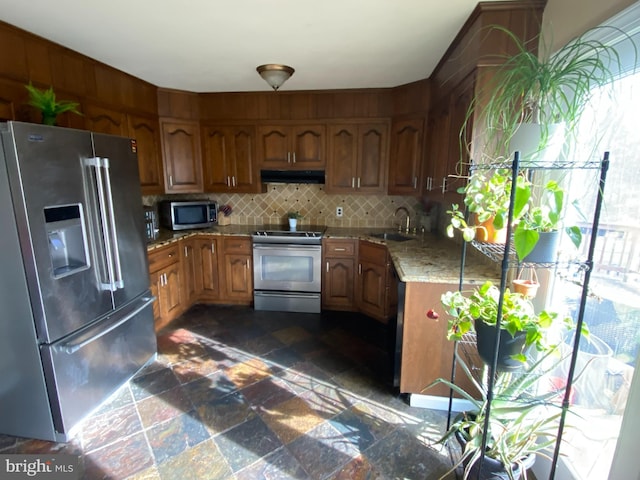 kitchen with stainless steel appliances, sink, light stone counters, and decorative backsplash