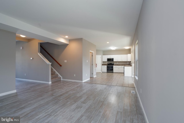 unfurnished living room with sink and light wood-type flooring