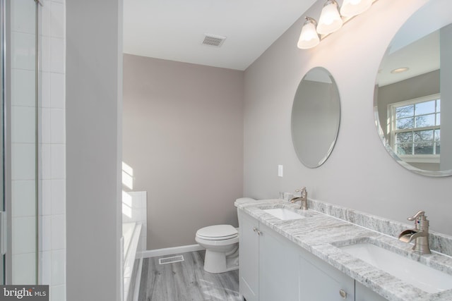 bathroom featuring hardwood / wood-style flooring, vanity, a bathing tub, and toilet