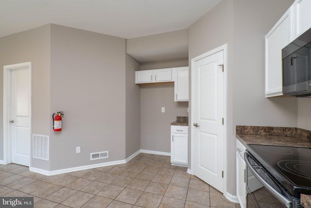 kitchen with light tile patterned flooring, black electric range, and white cabinets