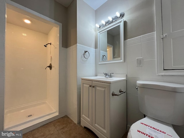 bathroom featuring tile walls, vanity, a shower, tile patterned floors, and toilet