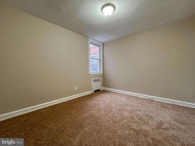 carpeted spare room featuring radiator heating unit