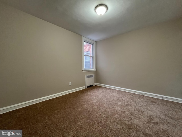 spare room featuring radiator heating unit and carpet