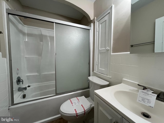 full bathroom featuring shower / bath combination with glass door, tile walls, vanity, tasteful backsplash, and toilet