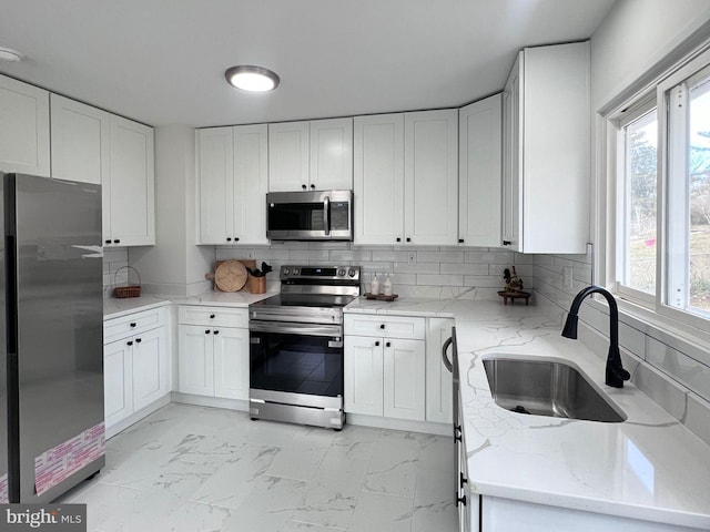 kitchen featuring tasteful backsplash, appliances with stainless steel finishes, sink, and white cabinets