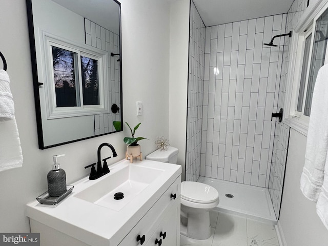 bathroom featuring tiled shower, vanity, and toilet