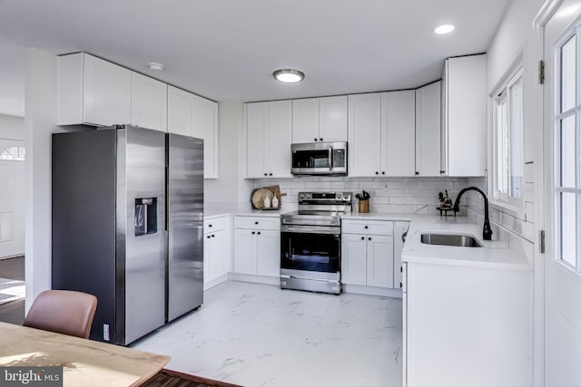 kitchen with sink, appliances with stainless steel finishes, white cabinetry, backsplash, and plenty of natural light