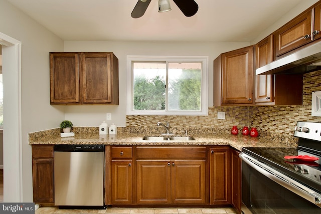 kitchen with sink, light stone counters, appliances with stainless steel finishes, ceiling fan, and backsplash