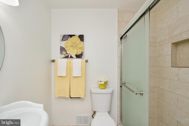 bathroom featuring an enclosed shower, sink, and toilet