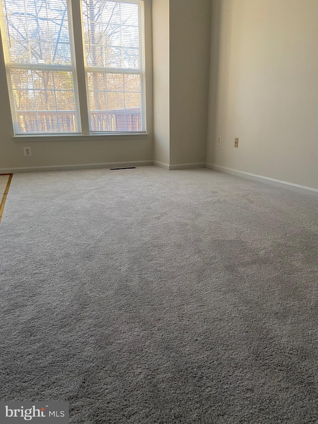 carpeted spare room featuring baseboards