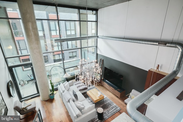 living room with hardwood / wood-style floors, a wall of windows, and a chandelier