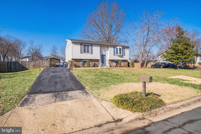 raised ranch with a detached carport, brick siding, driveway, and a front lawn