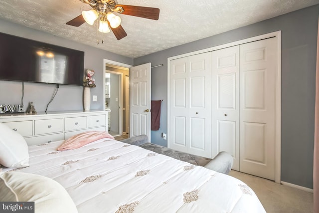 bedroom featuring a closet, a ceiling fan, light carpet, a textured ceiling, and baseboards